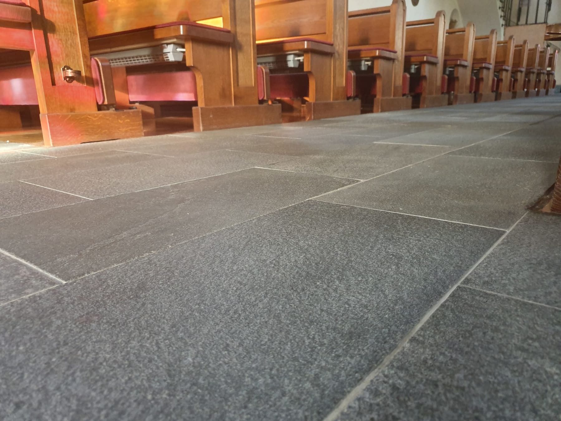 Natursteinboden im Kirchenschiff zwischen den Bankreihen nach der Reinigung.