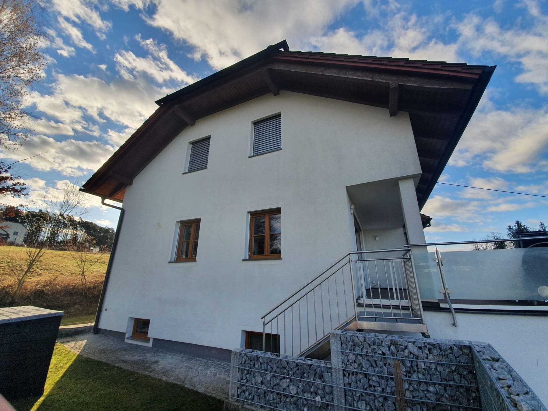 Putzfassade eines Einfamilienhauses nach der Reinigung, gleichmäßig hell und frei von Ablagerungen.