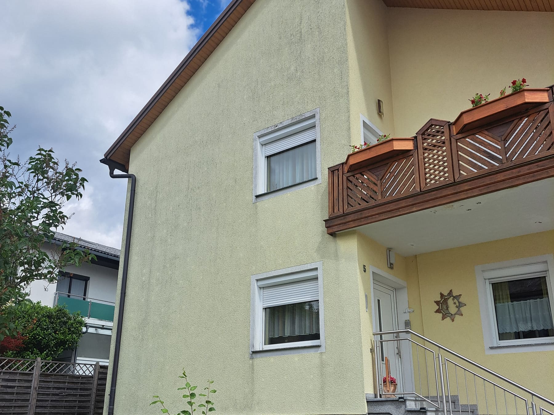 Verputzte Giebelfassade eines Wohnhauses vor der Reinigung, mit vergrauter, algig wirkender Oberfläche.