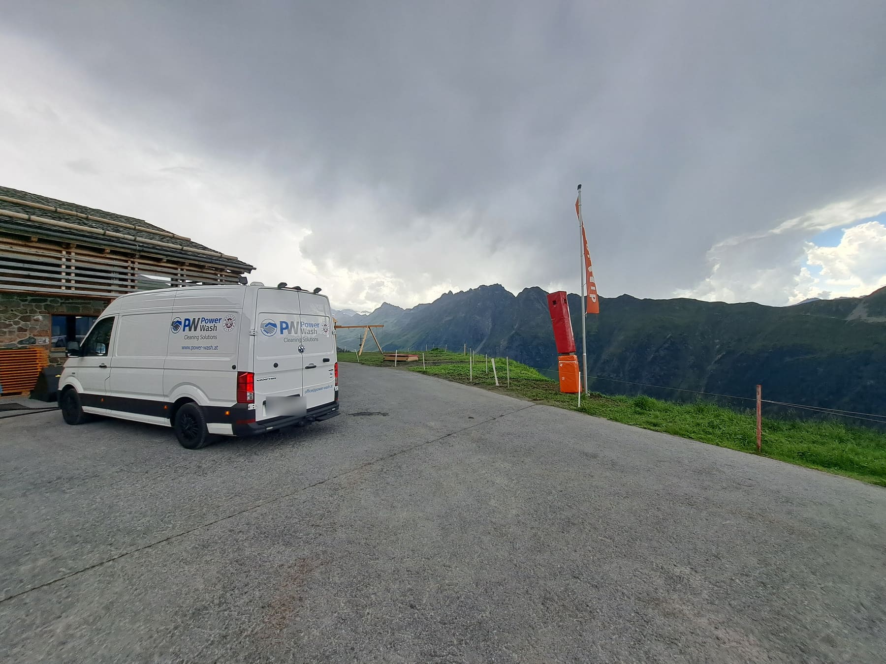 Beschriftetes Power Wash Firmenfahrzeug auf einem Einsatzort vor Bergkulisse; das Kennzeichen ist unkenntlich gemacht.