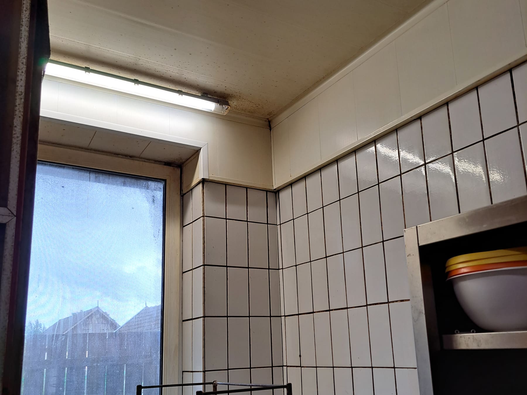 Dieselbe Küchenecke nach der Reinigung, mit weißer Decke und sauberen Wandfliesen.