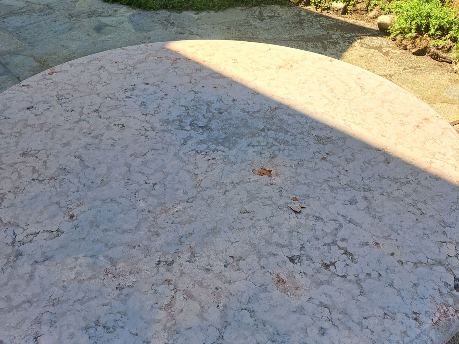 Runde Marmortischplatte im Freien vor der Sanierung, stumpf und ausgewaschen.